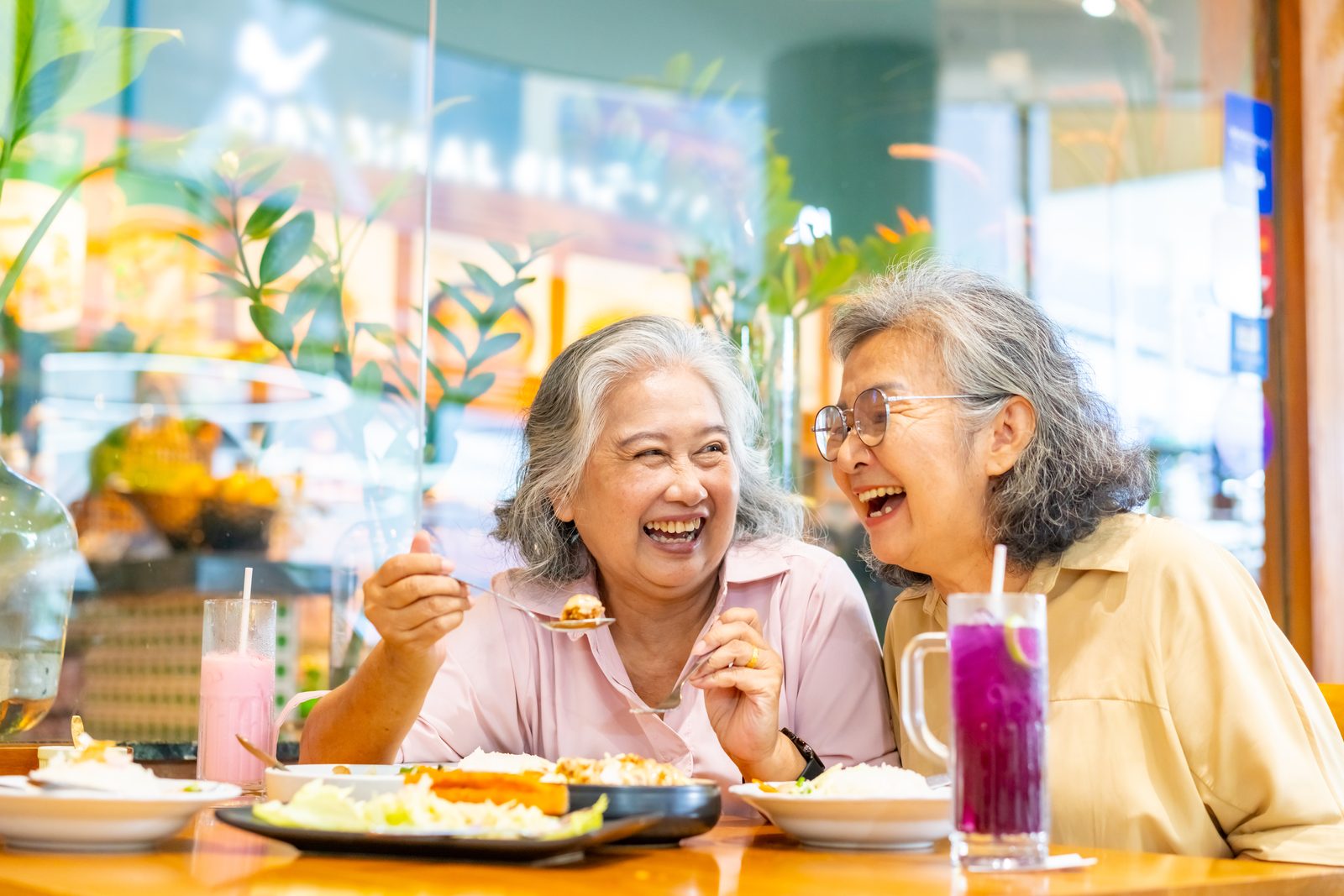兩位銀髮姊妹在餐廳開懷大笑用餐