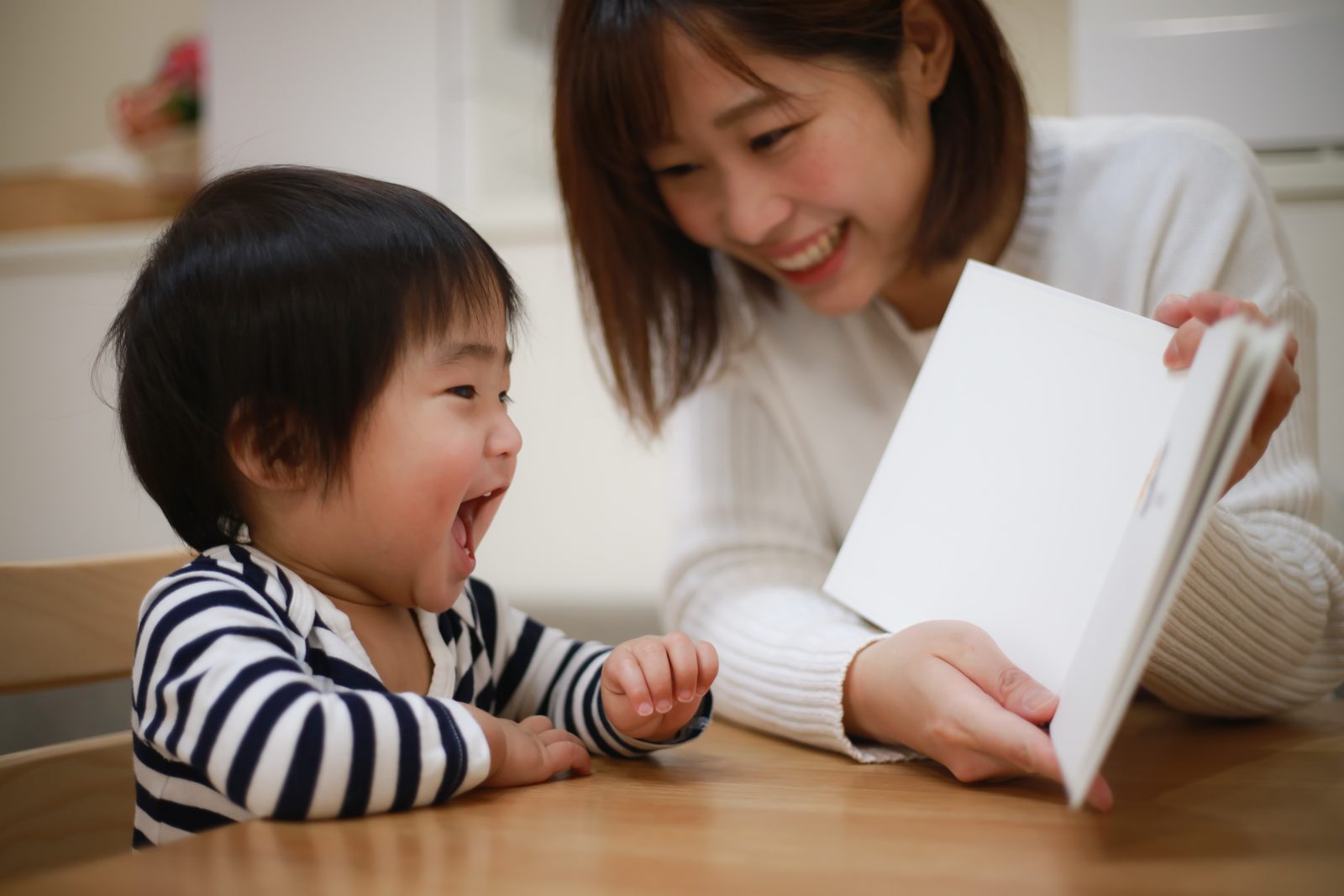 大人拿著圖卡與幼兒互動，孩子興奮地張嘴回應