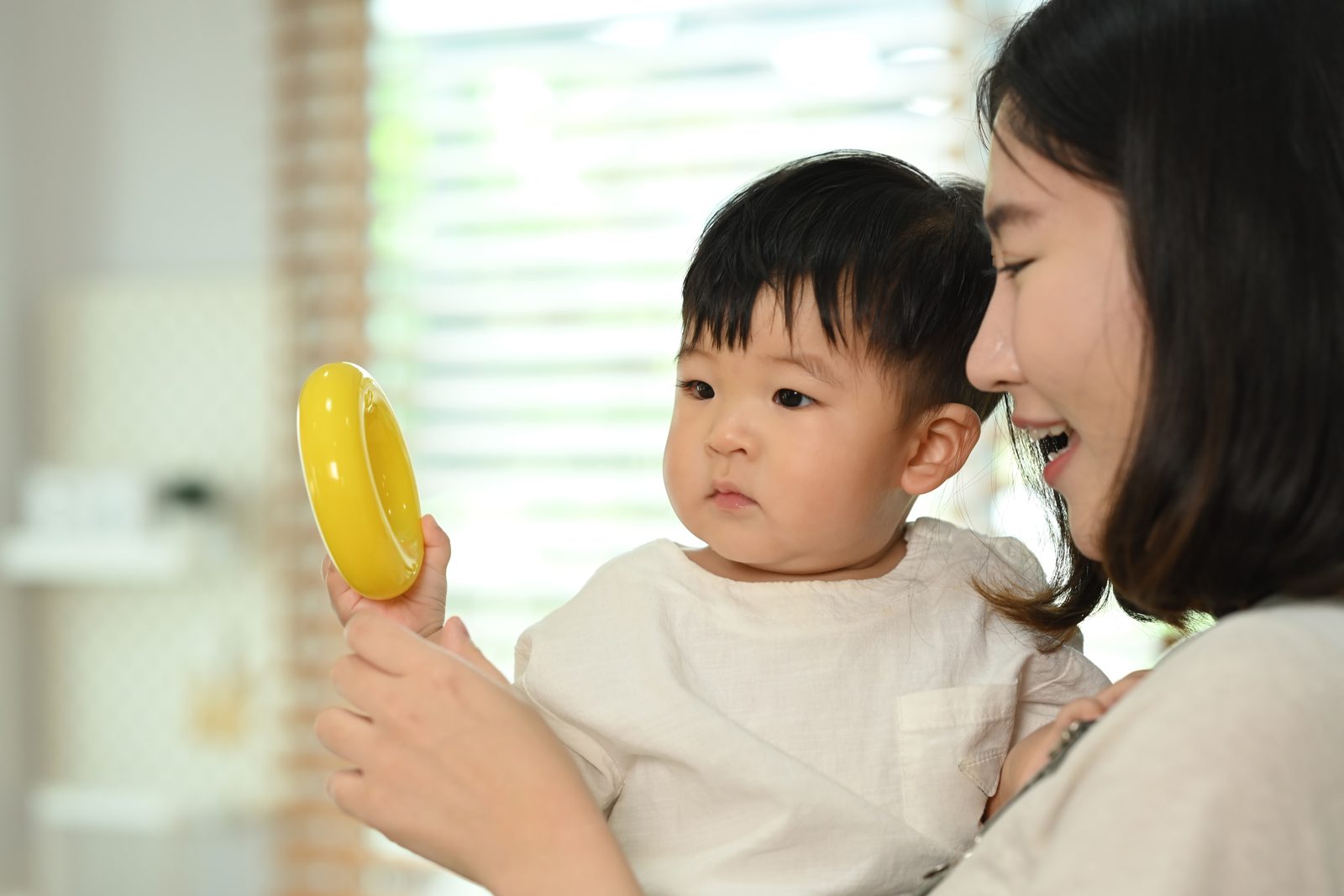 媽媽拿黃色玩具吸引幼兒注意，觀察孩子對聲音與物品的反應